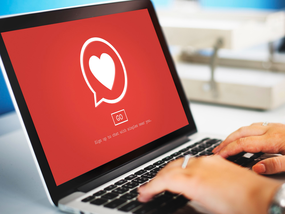 Person using a laptop showing a dating chat icon for Personal Dating Reputation Management