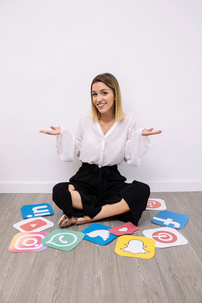 Smiling woman sitting on floor surrounded by social media icons, discussing media reputation topics.