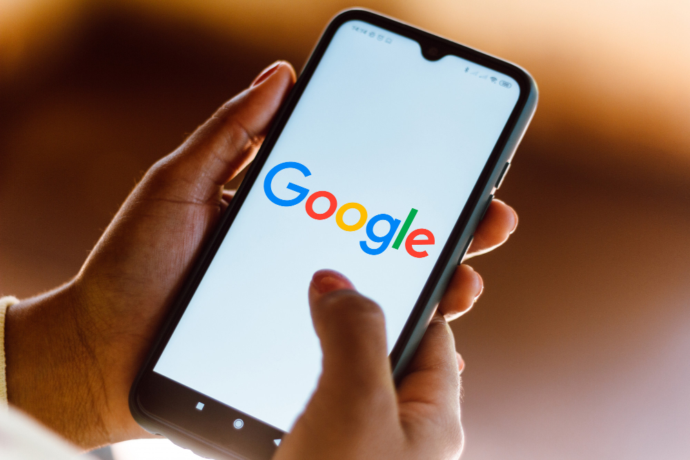 Person holding a smartphone with Google logo symbolizing efforts to remove news article from Google