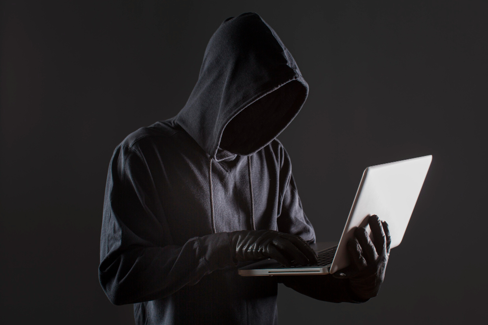 Dark web hacker using a laptop — dark web monitoring illustration.