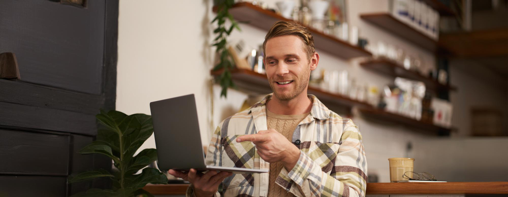 Professionals 2 Smiling man pointing at laptop screen in cafe while discussing reputation management for professionals