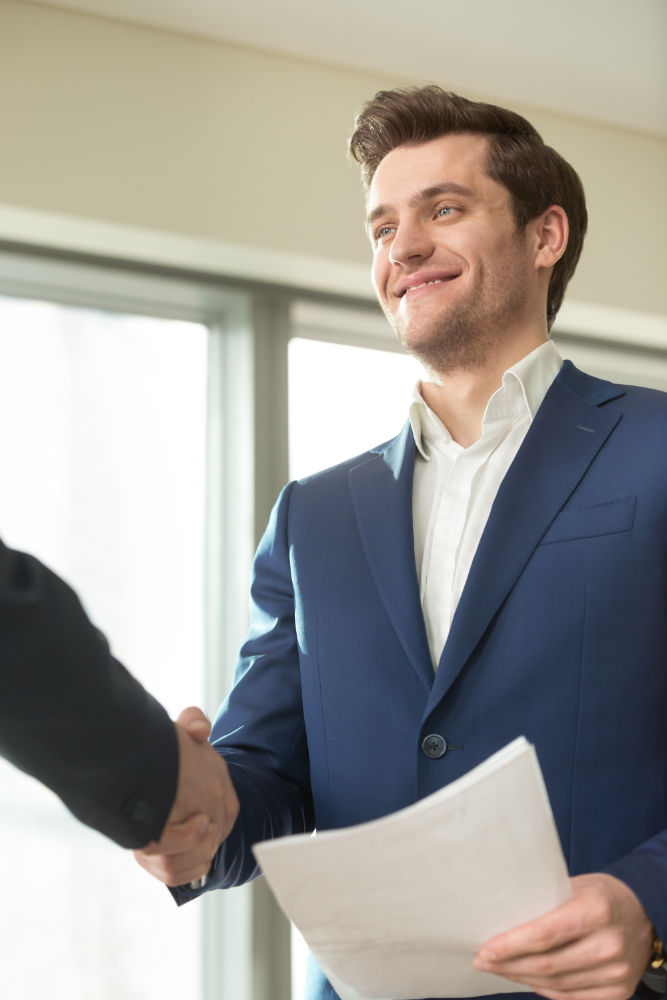 Smiling businessman shaking hands after an interview, symbolizing success in clearing background check