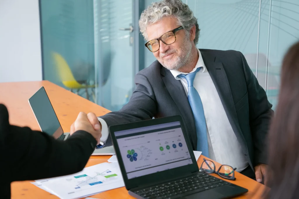 grey haired caucasian businessman handshaking smiling 1